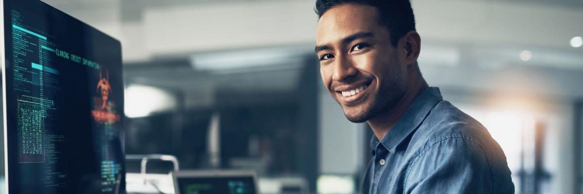 IT manager working on computer and smiling at camera