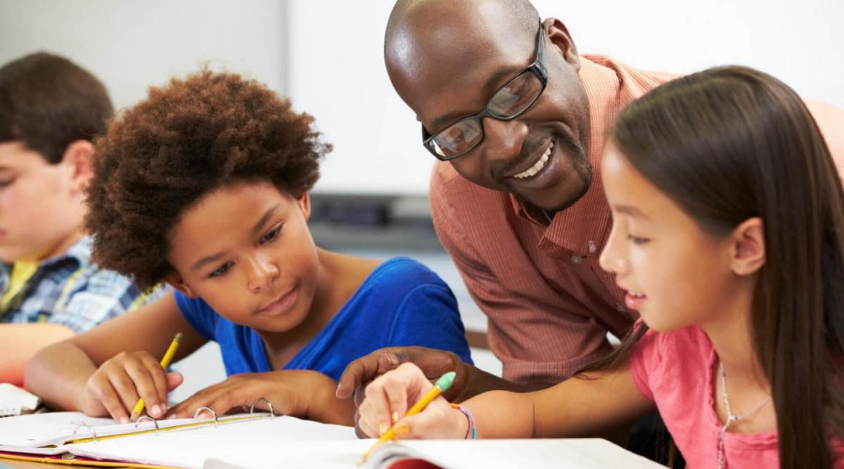 teacher helping two students in school